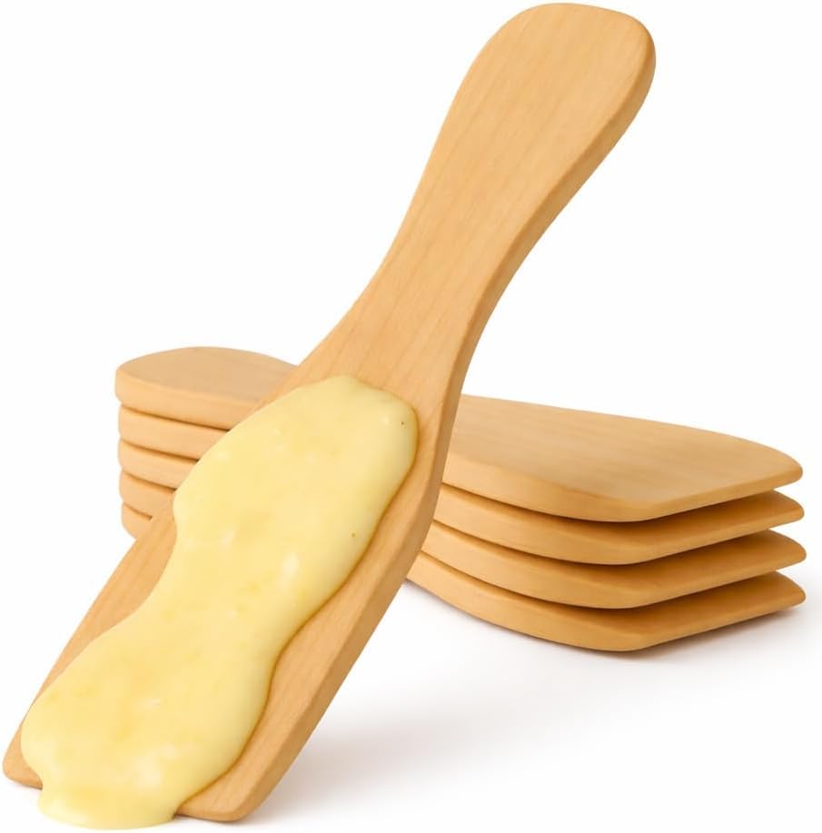 Dix spatules en bois alignées près d’un appareil à raclette et de poêlons.