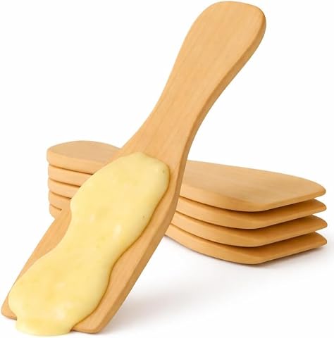 Dix spatules en bois alignées près d’un appareil à raclette et de poêlons.