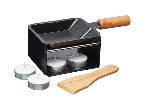 Mini raclette Artesa en métal noir avec poêle, spatule en bois et deux bougies sur une table claire.