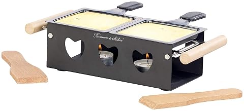 Appareil à raclette noir à bougies avec deux poêlons antiadhésifs et une spatule sur une table en bois.