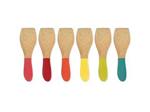 Six spatules à raclette en bambou aux manches colorés posées près d’un poêlon